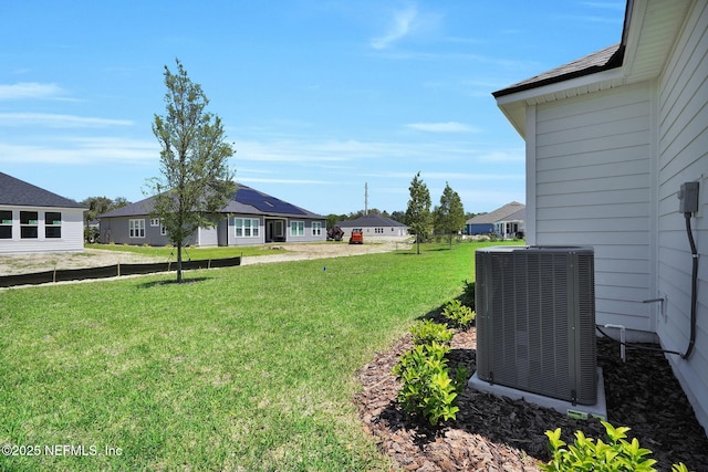 view of grassy yard featuring central AC unit and a residential view