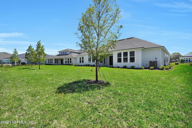 rear view of house featuring central air condition unit and a yard