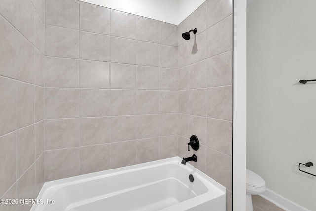bathroom with toilet, shower / washtub combination, and baseboards