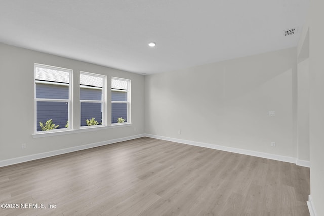 empty room with light wood finished floors, baseboards, and recessed lighting