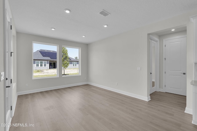 empty room with light wood-type flooring, baseboards, a textured ceiling, and recessed lighting