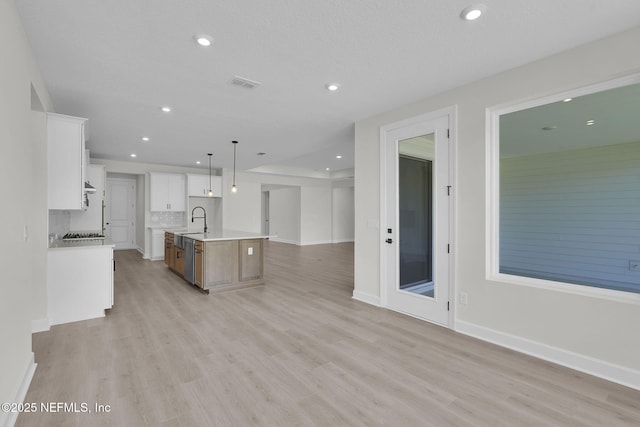 unfurnished living room with a sink, light wood-style flooring, recessed lighting, and baseboards