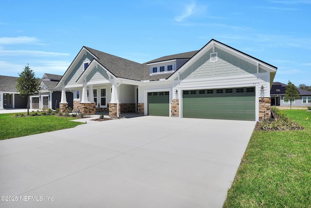 craftsman-style house featuring stone siding, a garage, concrete driveway, a front yard, and a porch