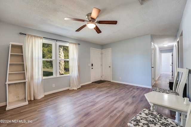 unfurnished living room featuring a textured ceiling, light wood-type flooring, and ceiling fan