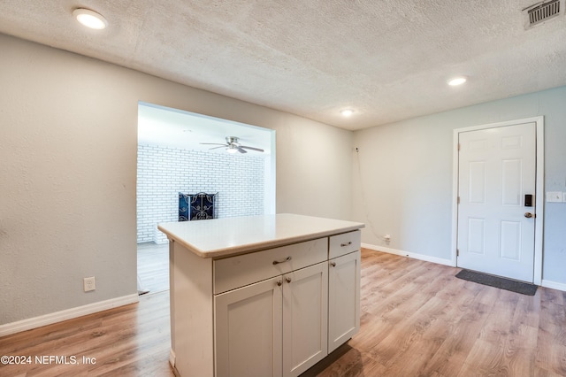 kitchen with a center island, light wood-type flooring, a textured ceiling, and white cabinetry