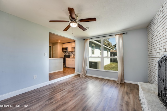 unfurnished living room featuring a textured ceiling, light hardwood / wood-style floors, a brick fireplace, and ceiling fan