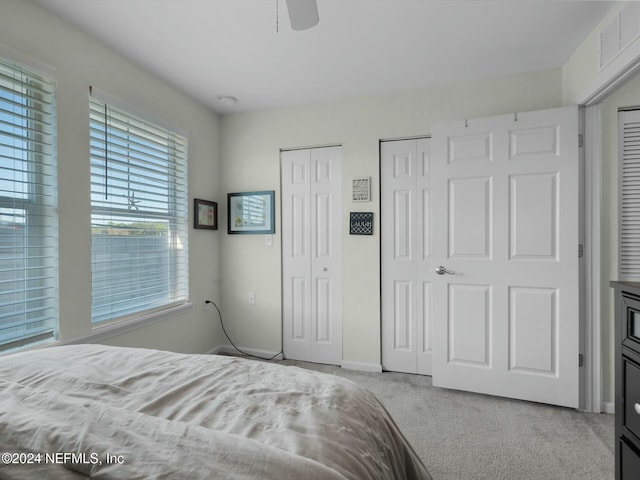 carpeted bedroom with two closets and ceiling fan