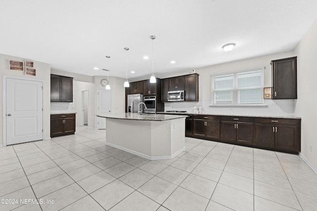 kitchen with pendant lighting, a kitchen island with sink, sink, dark brown cabinetry, and stainless steel appliances