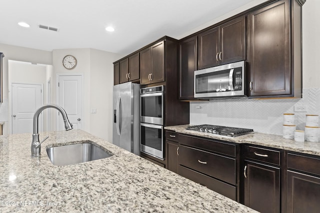 kitchen with dark brown cabinetry, light stone countertops, sink, and appliances with stainless steel finishes