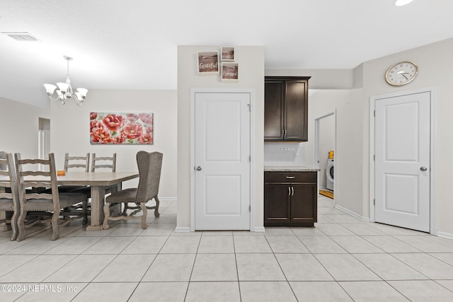 kitchen featuring light stone countertops, dark brown cabinetry, a chandelier, hanging light fixtures, and light tile patterned flooring