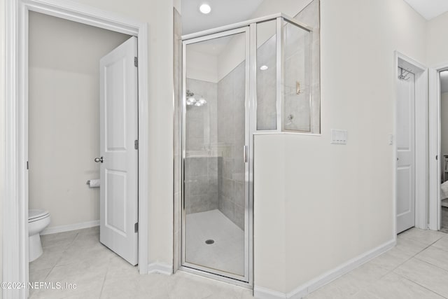 bathroom with tile patterned flooring, toilet, and a shower with door