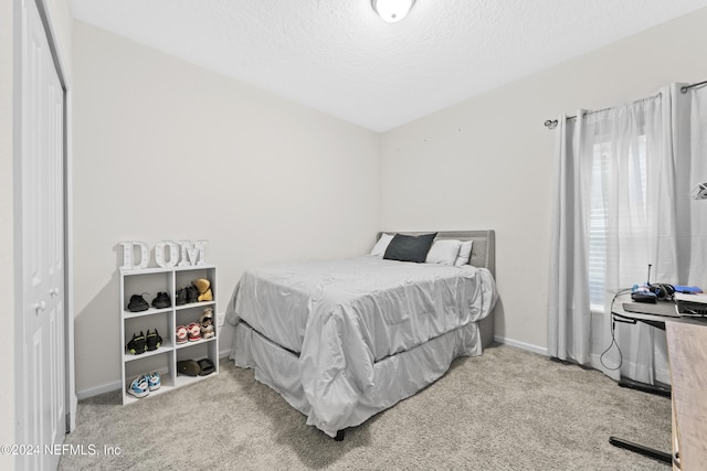 bedroom featuring light colored carpet, a textured ceiling, and a closet