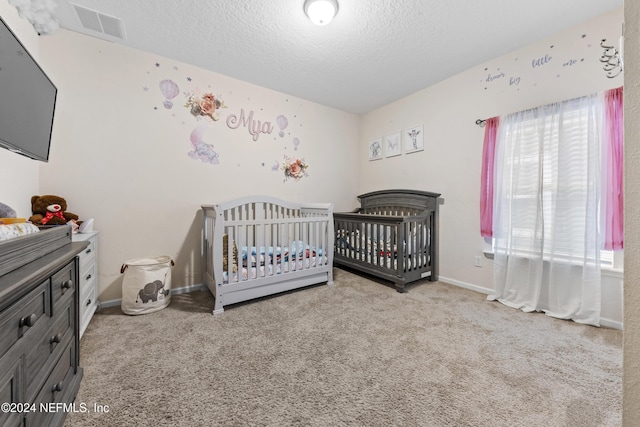 carpeted bedroom featuring a crib and a textured ceiling