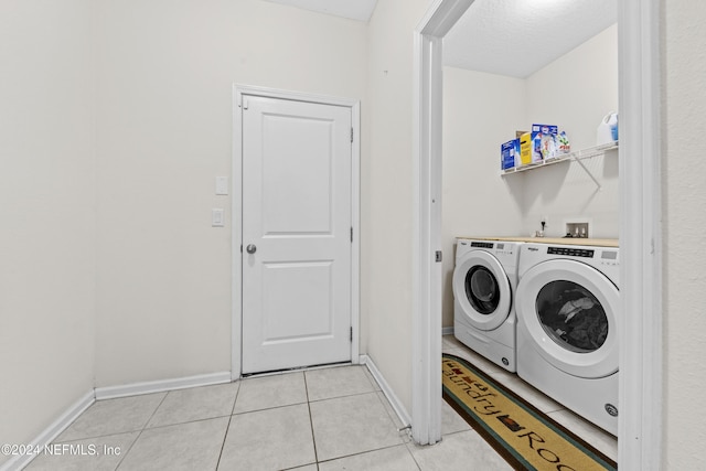 washroom with washer and dryer, light tile patterned floors, and a textured ceiling