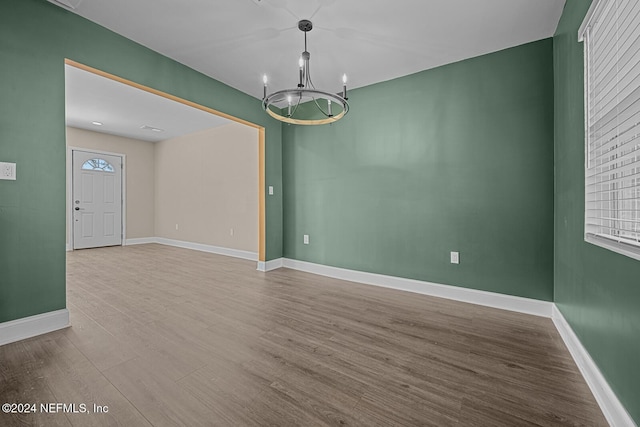 spare room with hardwood / wood-style floors and an inviting chandelier