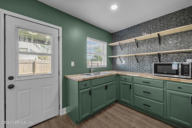 interior space with wood counters, sink, green cabinetry, tasteful backsplash, and wood-type flooring