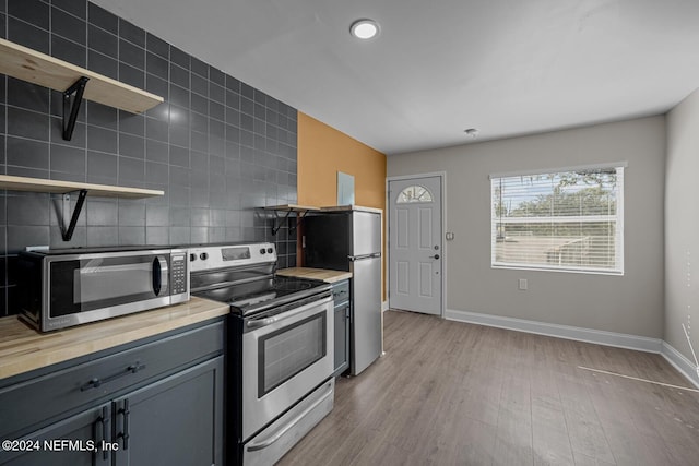 kitchen featuring gray cabinetry, tasteful backsplash, appliances with stainless steel finishes, and light hardwood / wood-style flooring