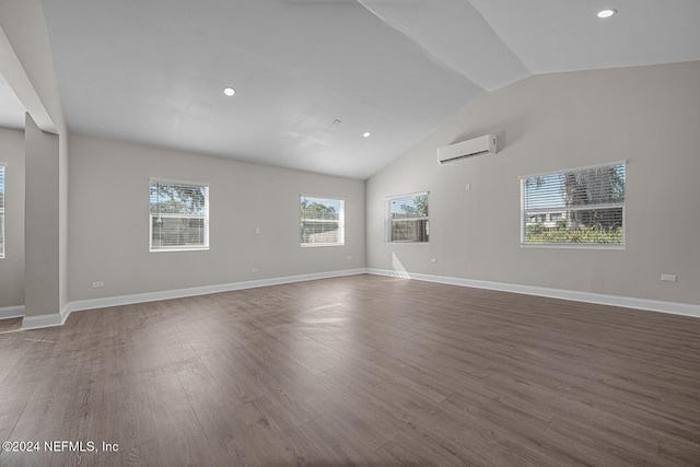 empty room with high vaulted ceiling, wood-type flooring, and a wall unit AC