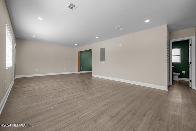 unfurnished room with electric panel and light hardwood / wood-style flooring