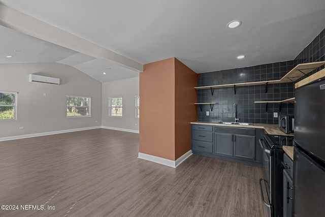 kitchen featuring a wall mounted air conditioner, lofted ceiling, black appliances, sink, and wood-type flooring