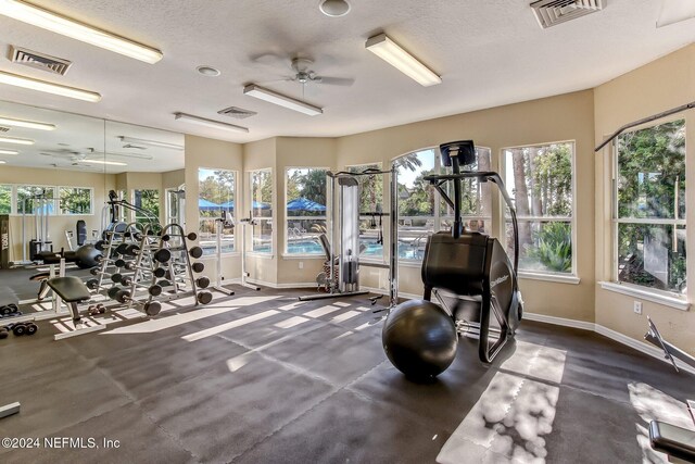 workout area with ceiling fan, a healthy amount of sunlight, and a textured ceiling