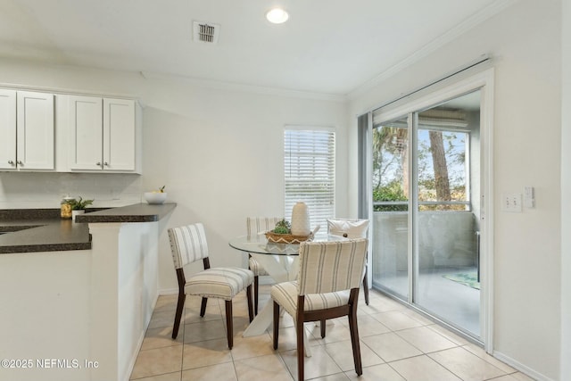 dining area with ornamental molding and light tile patterned floors