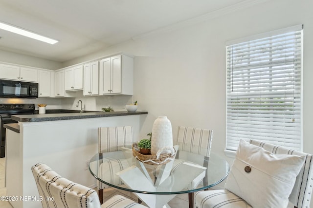 kitchen featuring black appliances, sink, white cabinets, ornamental molding, and kitchen peninsula