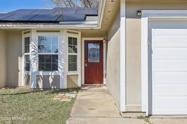 doorway to property with a garage and solar panels