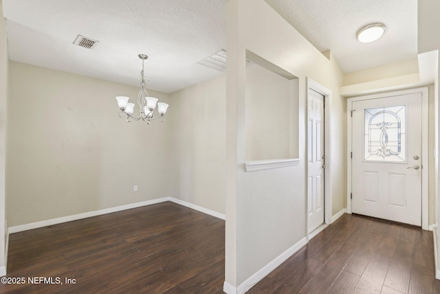 entryway with dark hardwood / wood-style floors, a textured ceiling, and a chandelier