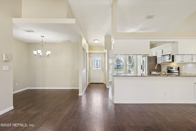 kitchen with hanging light fixtures, light stone countertops, appliances with stainless steel finishes, white cabinetry, and kitchen peninsula