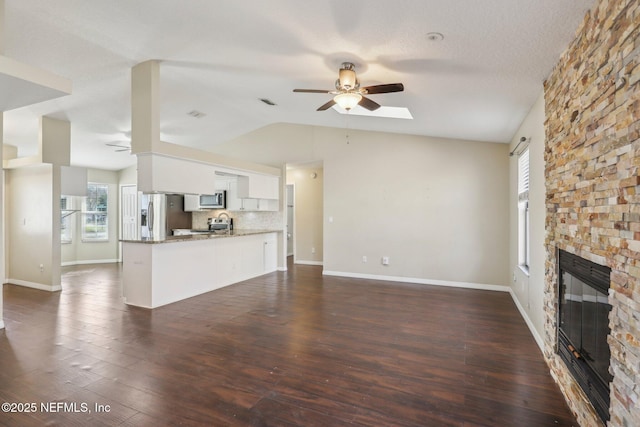 unfurnished living room with dark hardwood / wood-style floors, lofted ceiling, a fireplace, and a wealth of natural light