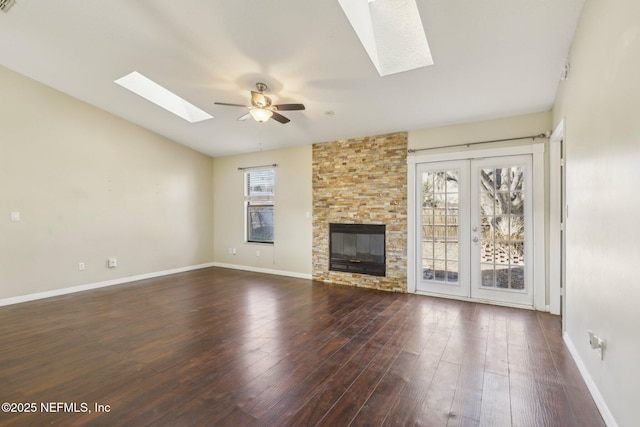 unfurnished living room featuring ceiling fan, a fireplace, dark wood-type flooring, and vaulted ceiling with skylight