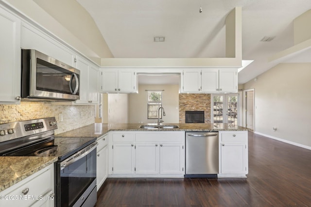 kitchen with white cabinetry, sink, kitchen peninsula, vaulted ceiling, and appliances with stainless steel finishes