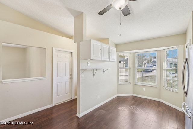 unfurnished dining area featuring ceiling fan, dark hardwood / wood-style floors, a textured ceiling, and vaulted ceiling