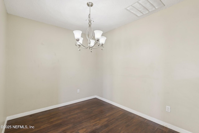 unfurnished room featuring dark wood-type flooring and an inviting chandelier