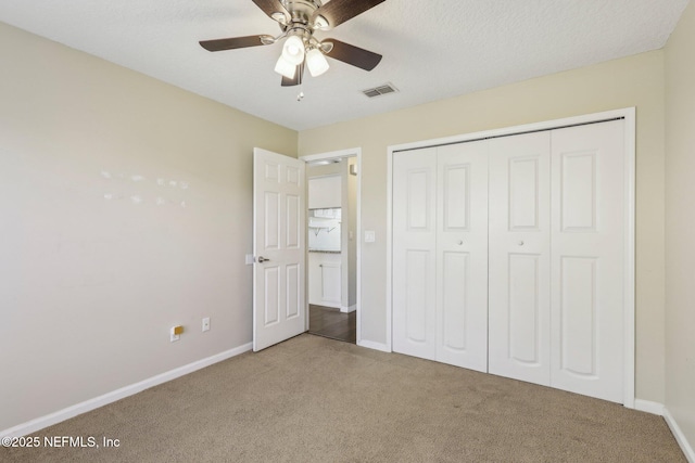 unfurnished bedroom with carpet, a textured ceiling, a closet, and ceiling fan