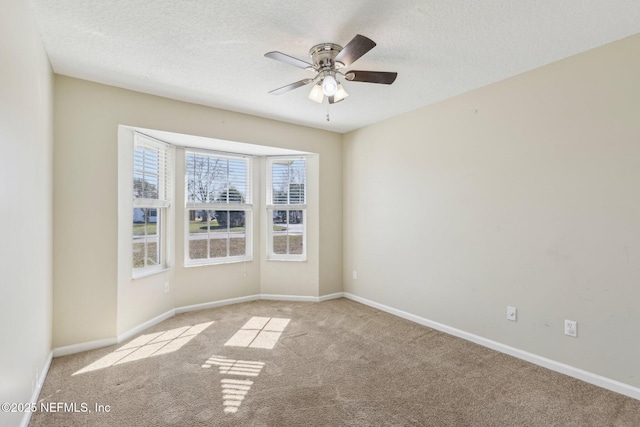 empty room with ceiling fan, light colored carpet, and a textured ceiling