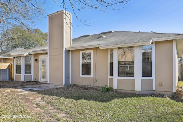 rear view of house featuring a lawn and central AC