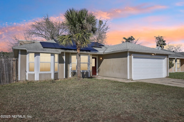 view of front of house with a lawn, a garage, and solar panels