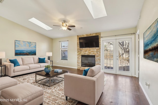 living room featuring ceiling fan, a fireplace, hardwood / wood-style floors, and lofted ceiling with skylight