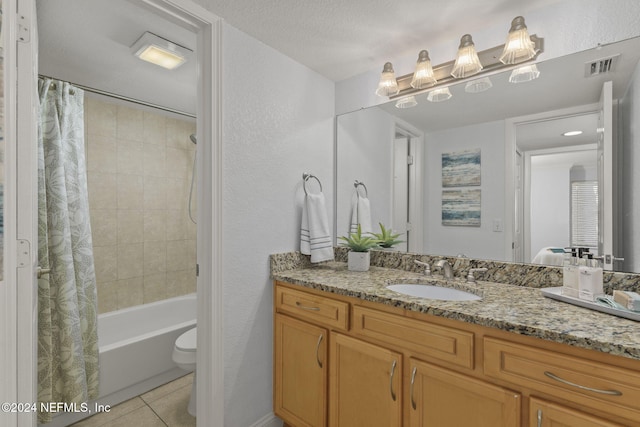 full bathroom with tile patterned floors, a textured ceiling, toilet, shower / bath combo with shower curtain, and vanity