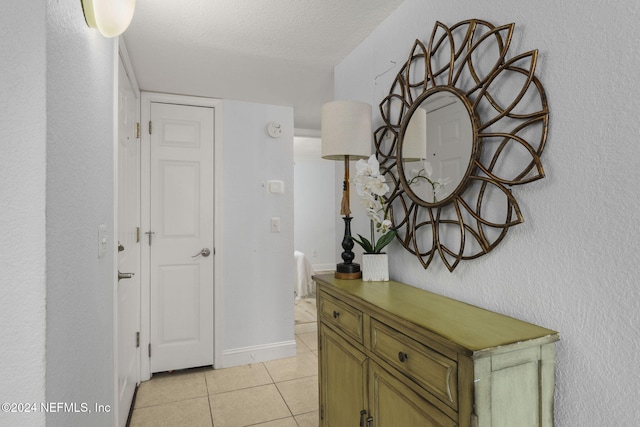 corridor with light tile patterned flooring and a textured ceiling