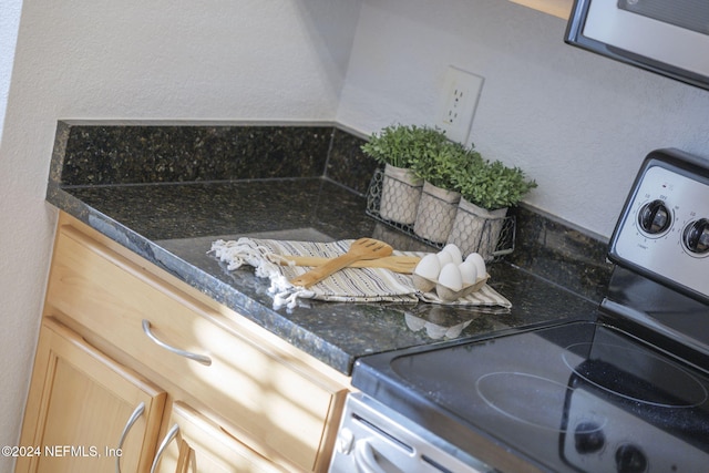 details with light brown cabinets and white range with electric stovetop