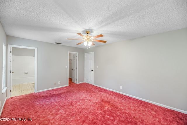 unfurnished bedroom with a textured ceiling, a walk in closet, and ceiling fan