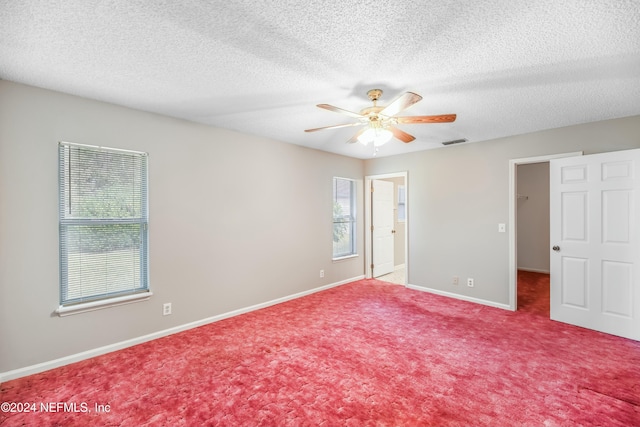 empty room with carpet flooring, a textured ceiling, and plenty of natural light