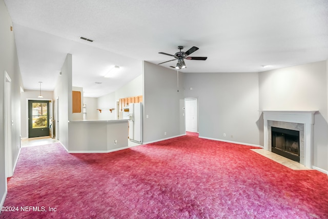 unfurnished living room featuring light colored carpet, vaulted ceiling, ceiling fan, and a tiled fireplace