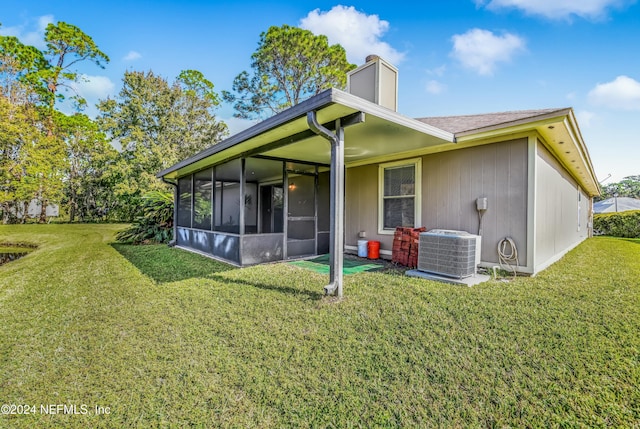 back of house with central air condition unit, a sunroom, and a yard