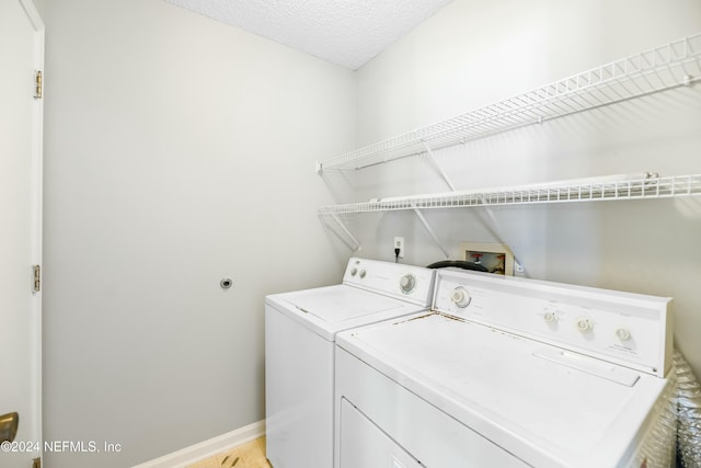 laundry room featuring a textured ceiling, light hardwood / wood-style flooring, and washer and clothes dryer