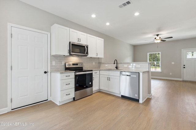 kitchen with white cabinetry, light hardwood / wood-style floors, kitchen peninsula, appliances with stainless steel finishes, and sink