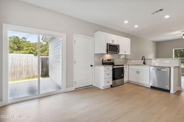 kitchen with white cabinets, appliances with stainless steel finishes, light hardwood / wood-style floors, decorative backsplash, and sink